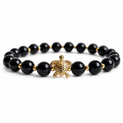 Black Onyx stone beaded bracelet with a gold turtle charm on a white background