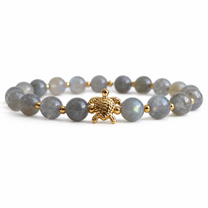 Bracelet with labradorite stone beads and a gold turtle charm on a white background