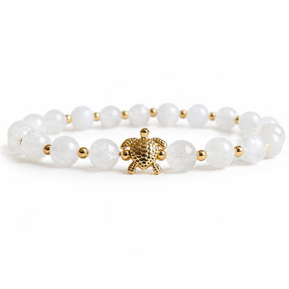 White beaded bracelet with a gold turtle charm on a white background