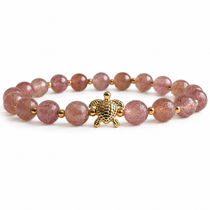 Bracelet with pink beads and a gold turtle charm on a white background