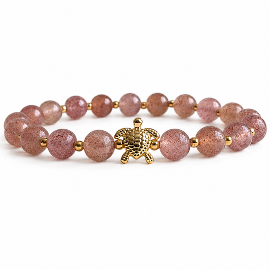 Bracelet with pink beads and a gold turtle charm on a white background