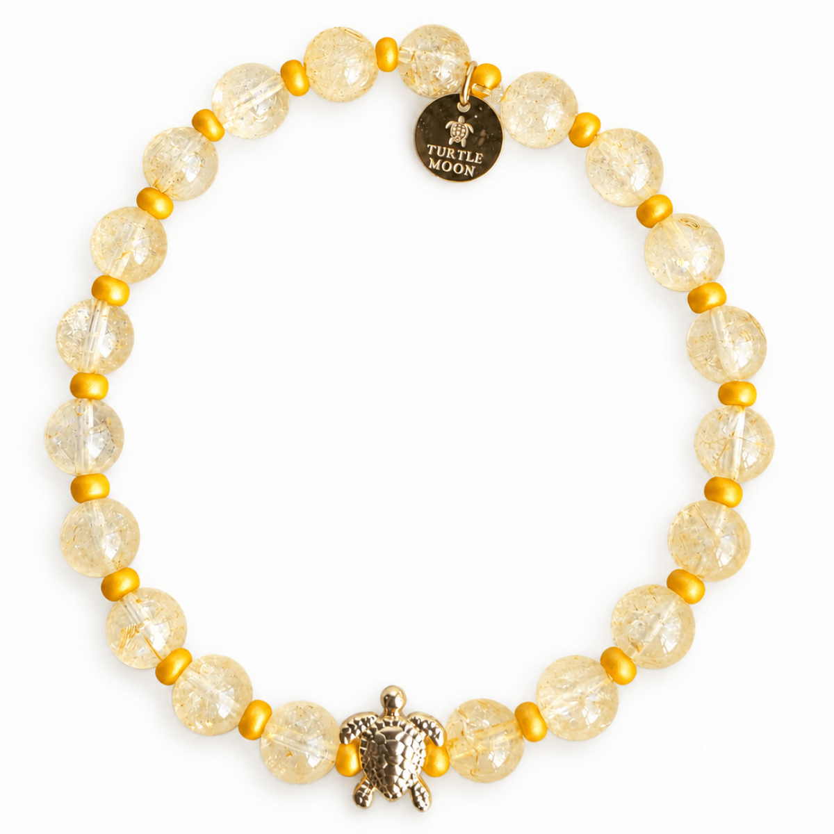 A beaded stretch bracelet featuring citrine quartz crystal beads, small yellow  spacer beads, a textured gold turtle charm, and a round gold disc charm engraved with 'TURTLE MOON'.